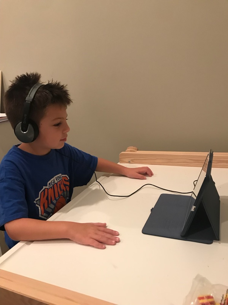 Boy in headphones at a teletherapy session on a tablet